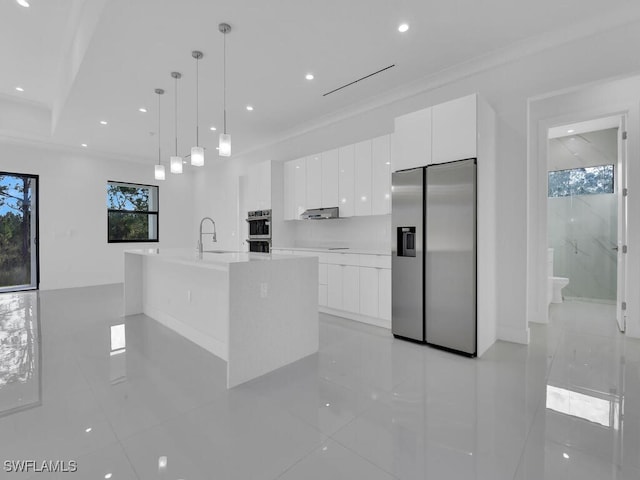 kitchen with white cabinetry, hanging light fixtures, stainless steel appliances, a center island with sink, and light tile patterned flooring