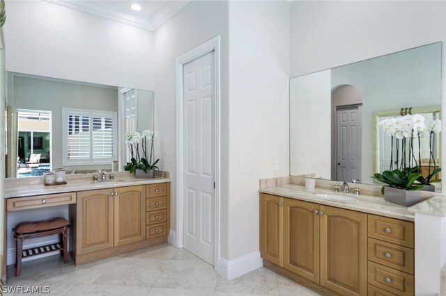 bathroom featuring crown molding, two vanities, and a sink