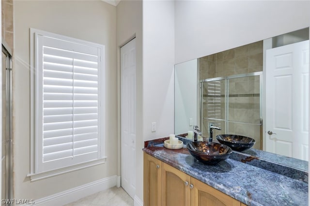 full bath featuring a stall shower, baseboards, and vanity