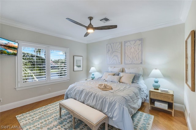 bedroom with ornamental molding, visible vents, baseboards, and wood finished floors