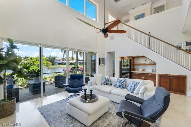 living area featuring visible vents, a water view, a wealth of natural light, and a ceiling fan