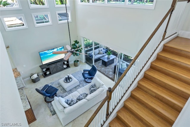 living area with stairway, wood finished floors, a towering ceiling, and baseboards