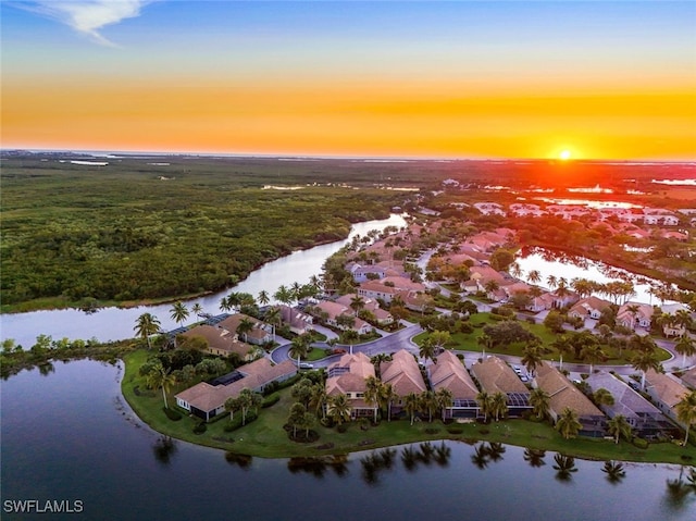 aerial view at dusk with a water view and a residential view