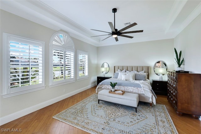 bedroom featuring a ceiling fan, baseboards, a raised ceiling, and wood finished floors