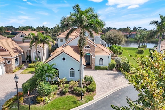 mediterranean / spanish house featuring decorative driveway and a water view