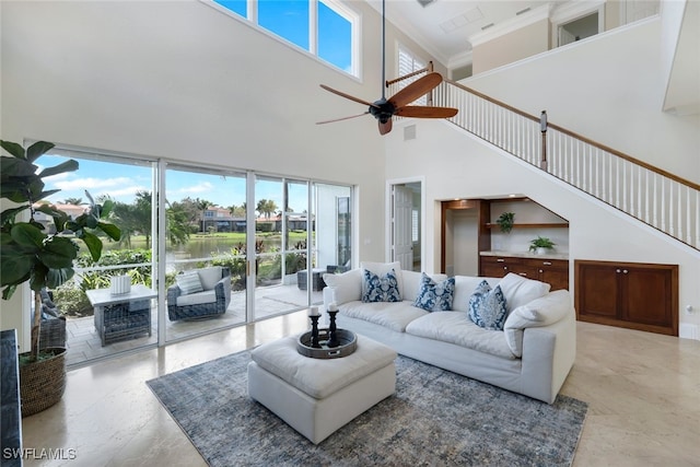 living area with visible vents, a ceiling fan, and ornamental molding