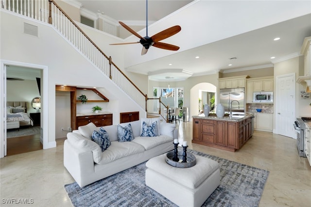 living room with arched walkways, recessed lighting, visible vents, stairs, and crown molding