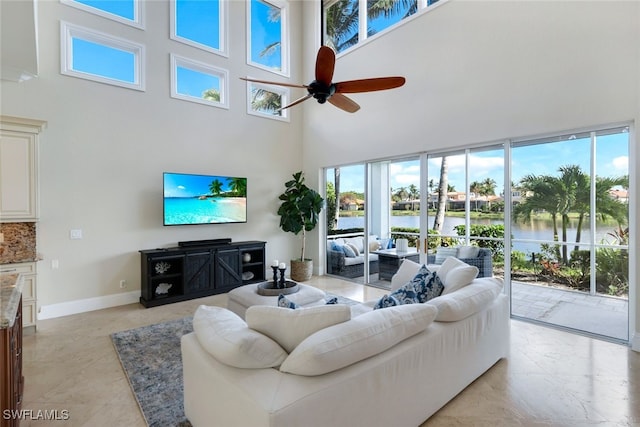 living room with ceiling fan, a towering ceiling, and baseboards