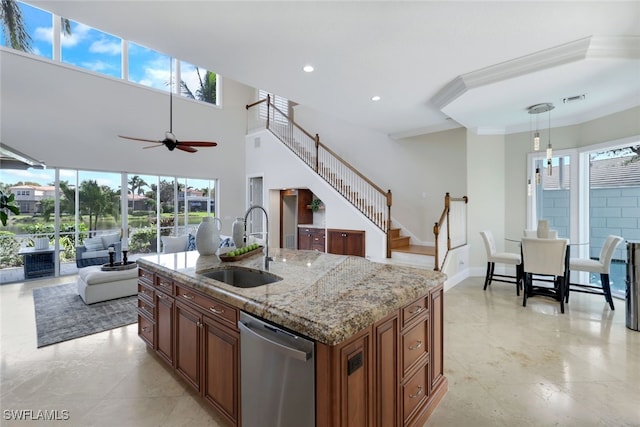 kitchen featuring open floor plan, stainless steel dishwasher, a sink, and a healthy amount of sunlight