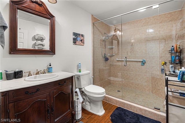 bathroom featuring vanity, a shower with door, hardwood / wood-style floors, and toilet