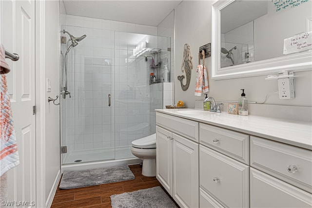 bathroom featuring a shower with shower door, oversized vanity, toilet, and hardwood / wood-style floors