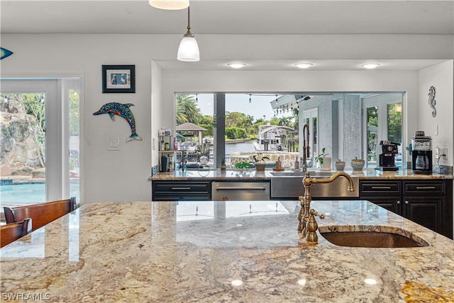 kitchen featuring sink, stainless steel dishwasher, hanging light fixtures, and light stone countertops