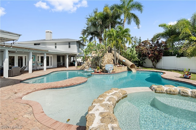 view of pool featuring french doors, a water slide, and a patio