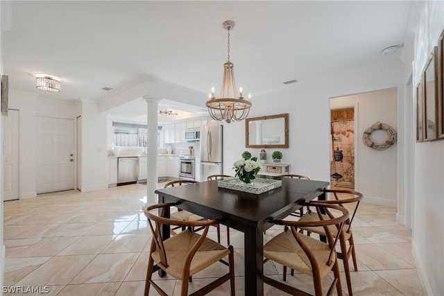 tiled dining room with decorative columns, an inviting chandelier, and crown molding