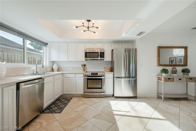 kitchen with an inviting chandelier, white cabinets, a raised ceiling, sink, and stainless steel appliances