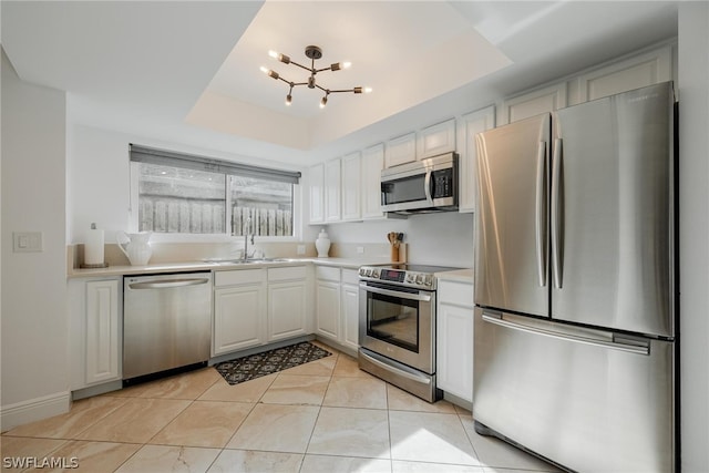 kitchen featuring white cabinets, stainless steel appliances, a raised ceiling, and sink