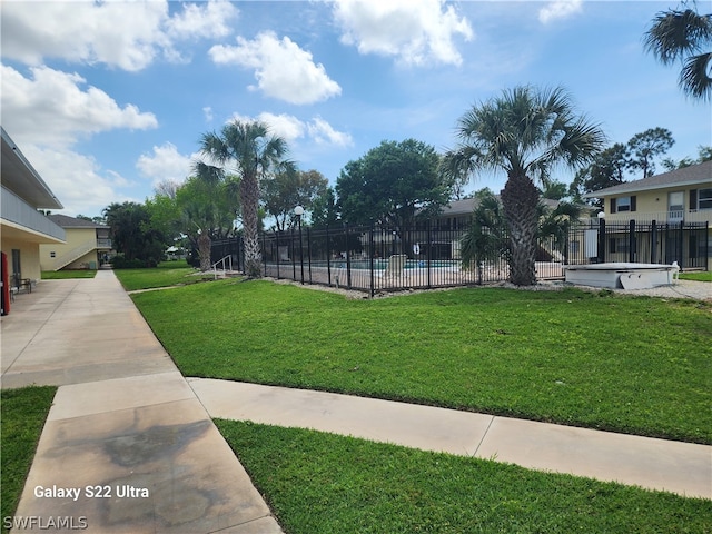 view of property's community with a pool and a lawn