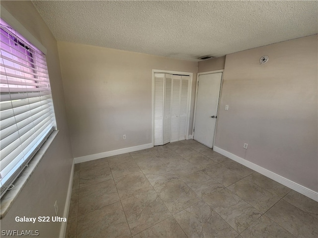 interior space with a textured ceiling, a closet, and light tile floors