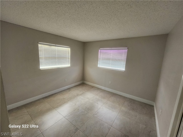 empty room with light tile floors and a textured ceiling