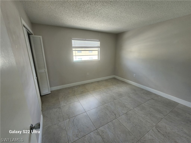 tiled spare room featuring a textured ceiling