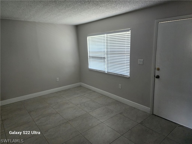 spare room featuring light tile floors and a textured ceiling