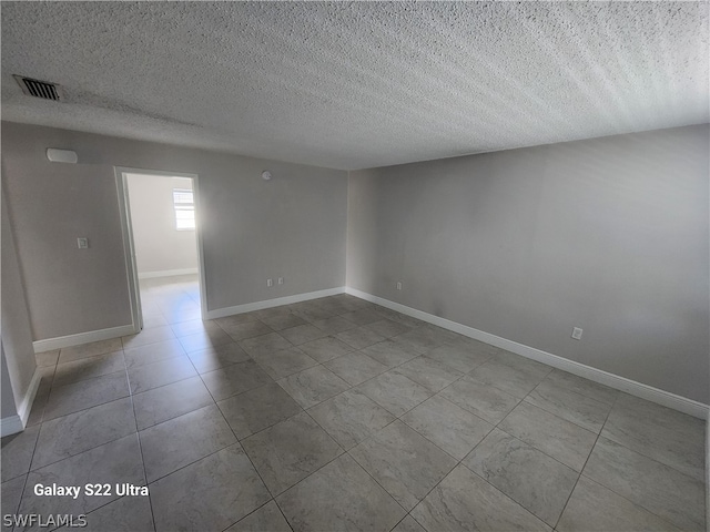 empty room with light tile floors and a textured ceiling