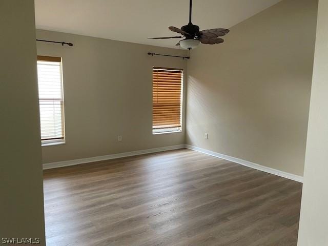 empty room featuring ceiling fan, a healthy amount of sunlight, and dark wood-type flooring