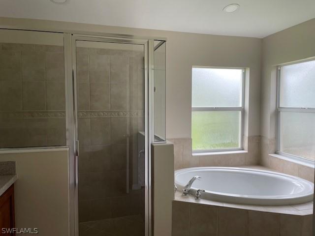 bathroom featuring plus walk in shower and vanity