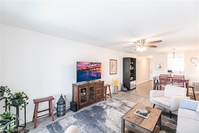 living room featuring ceiling fan with notable chandelier and light hardwood / wood-style floors