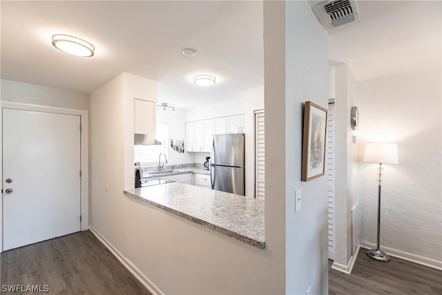 kitchen with dark hardwood / wood-style flooring, stainless steel fridge, white cabinetry, and light stone countertops