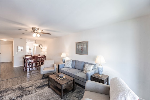 living room featuring ceiling fan and dark wood-type flooring