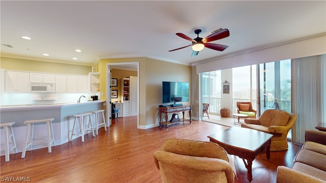 living room featuring light hardwood / wood-style flooring, ceiling fan, sink, and crown molding