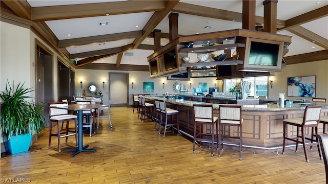 kitchen featuring ornamental molding, lofted ceiling with beams, a kitchen bar, and light wood-type flooring