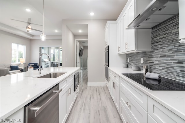 kitchen featuring wall chimney exhaust hood, backsplash, stainless steel appliances, sink, and light hardwood / wood-style floors