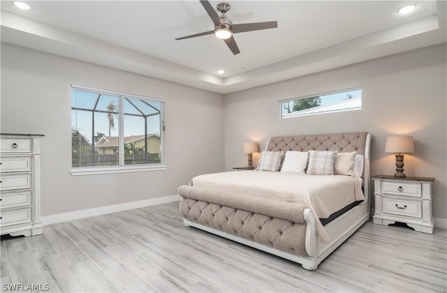 bedroom with baseboards, recessed lighting, a raised ceiling, and light wood-style floors