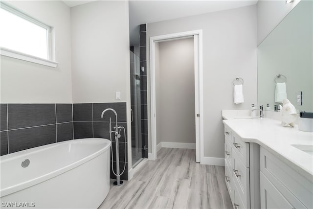 bathroom with a freestanding tub, wood finished floors, a sink, a stall shower, and double vanity