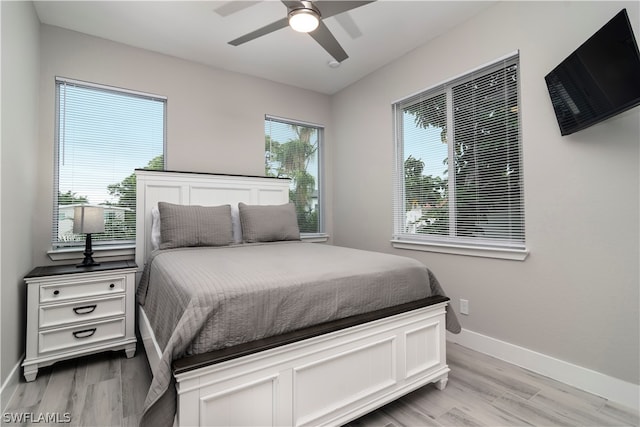 bedroom with light wood-type flooring, ceiling fan, and baseboards