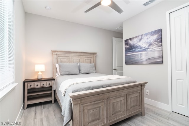 bedroom featuring light wood-style floors, visible vents, baseboards, and ceiling fan
