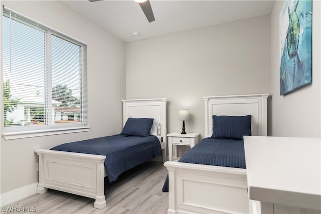 bedroom with light wood-style flooring, baseboards, and a ceiling fan