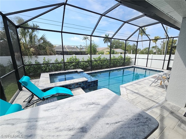 view of pool featuring a pool with connected hot tub, a patio, fence private yard, and a lanai