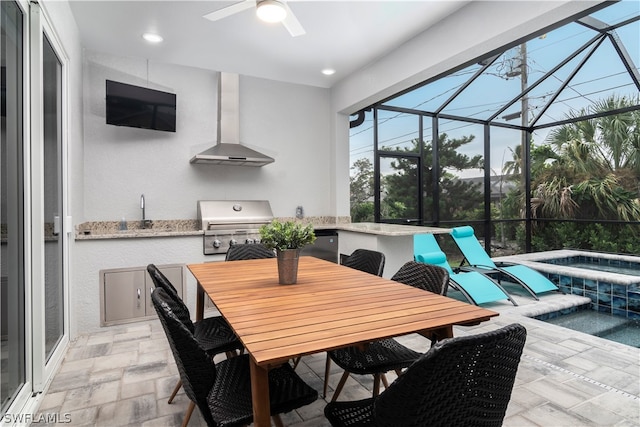 view of patio / terrace with exterior kitchen, a ceiling fan, grilling area, an in ground hot tub, and a lanai