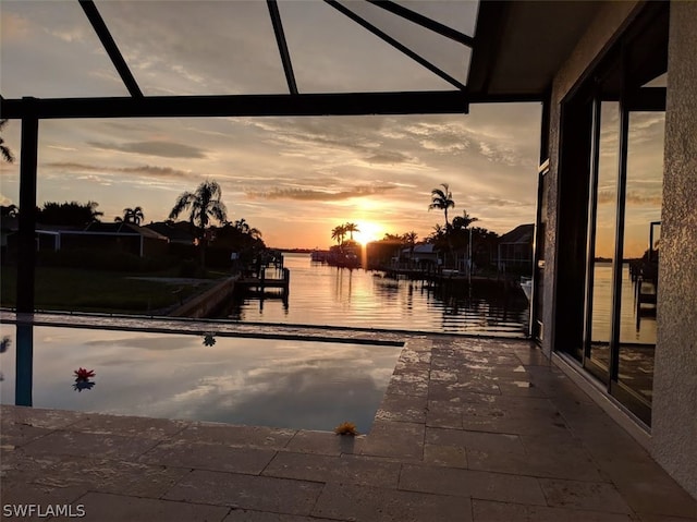 patio terrace at dusk with glass enclosure and a water view