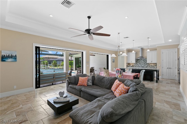 living room featuring a tray ceiling, ceiling fan, and ornamental molding