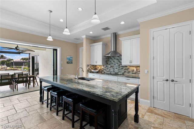 kitchen with white cabinets, a breakfast bar, wall chimney exhaust hood, and sink