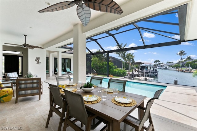 view of swimming pool with a water view, glass enclosure, ceiling fan, and a patio area