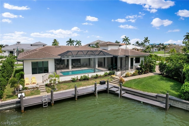 rear view of house with glass enclosure, a water view, a yard, and a patio