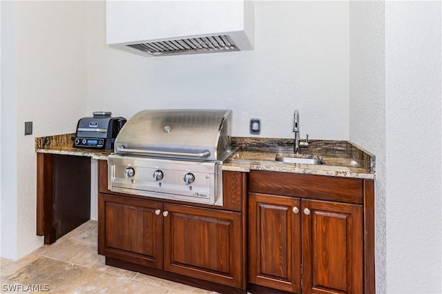 kitchen featuring stone countertops, ventilation hood, and sink