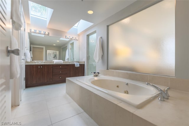 bathroom featuring a skylight, tile flooring, vanity, and tiled bath