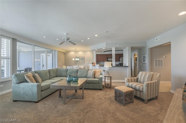 carpeted living room featuring ceiling fan with notable chandelier