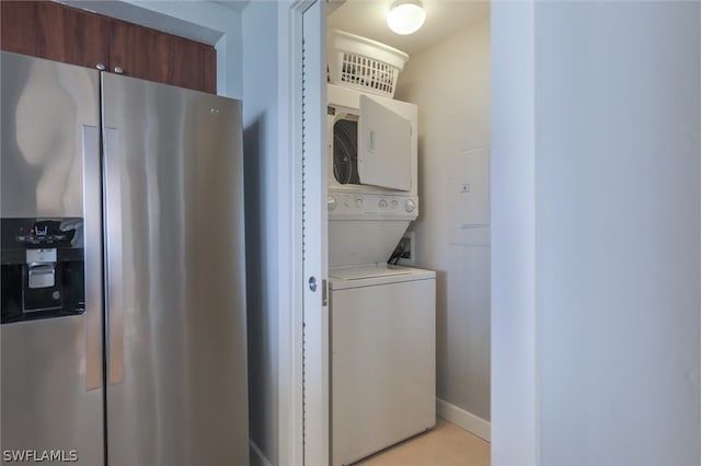 clothes washing area with light tile floors and stacked washing maching and dryer